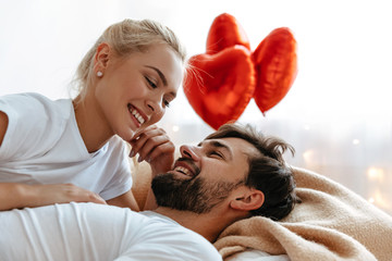 Love. Valentine's day. . Emotions. Young couple are looking at each other and laughing while lying together on the bed © PinkCoffee Studio