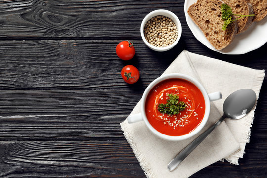 Fresh homemade tomato soup served with bread on wooden table, top view. Space for text