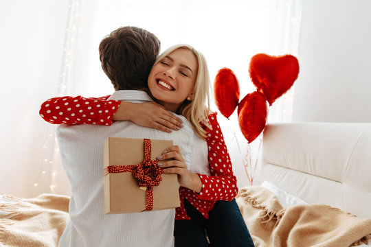Couple. Love. Valentine's day. Man and woman are hugging, she is holding a gift box and smiling