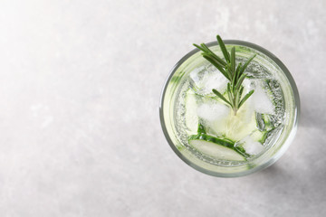 Glass of fresh cucumber water on grey background, top view. Space for text