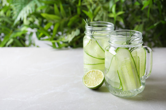 Mason jars of fresh cucumber water on table. Space for text