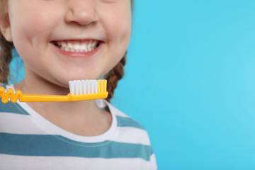 Little girl brushing teeth on color background, closeup. Space for text