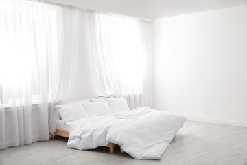 Fototapeta na wymiar Comfortable bed in light room. Interior design