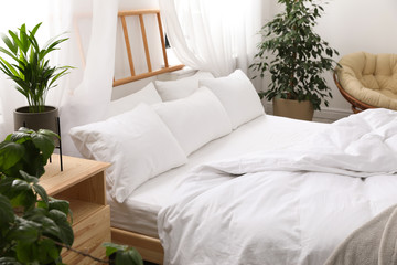Comfortable bed with soft pillows in room interior