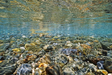 Pebbles underwater below water surface on the seashore, Mediterranean sea, France