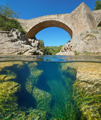 Fototapeta na wymiar River with an old stone bridge and eroded rocks underwater, split view half above and below water surface, Sant Llorenc de la Muga, Catalonia, Spain