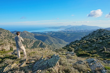 Obraz premium Spain landscape a man standing looking at view from the Albera mountain range with the Mediterranean sea and the Cap de Creus in background, Pyrenees, Catalonia, Alt Emporda