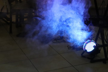 Blue LED spotlight on the floor with smoke in dark room close to cables and pillars with copy space. Party concept