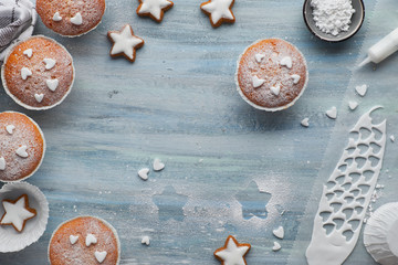 Top view of the table with sugar-sprinkled muffins, fondant icing and Christmas star cookies on blue