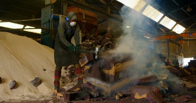 Worker breaking hot mold in foundry workshop