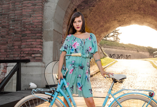 Young woman with retro bicycle posing back lit in the end of tunnel , bright sunset in background