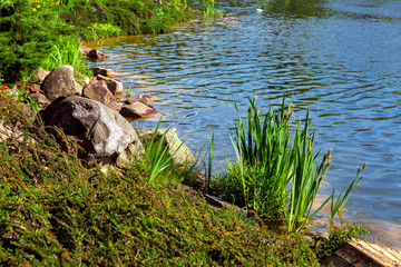 The beach is landscaped with stones and various shrubs near an artificial pond with water and waves.