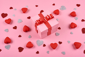 One pink box with red ribbon on pink background with hearts. Background for Valentines Day