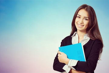 Fototapeta premium Young smiling woman holding blue notebook