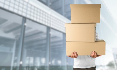 Delivery man carrying stacked boxes in front of face against