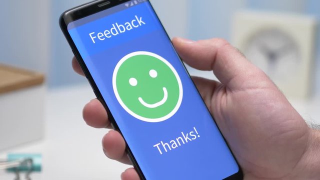 Giving a positive happy face review on a smartphone device. Face ratings concept