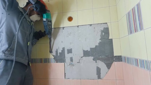 Demolition of old tiles with jackhammer. Renovation of old walls in the bathroom or kitchen