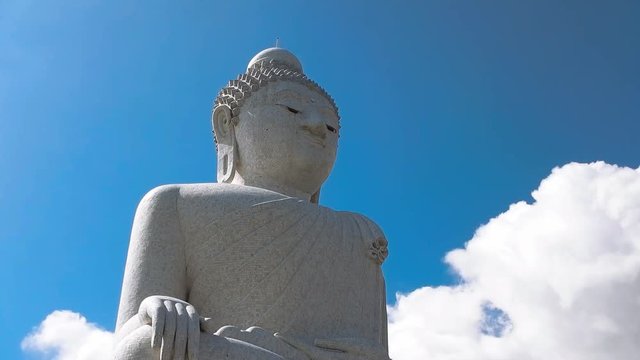 Big Buddha statue in Phuket, Thailand with a blue sky in background with passing white clouds.