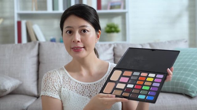 woman blogger showing makeup highlighter palette in live streaming at home. young girl vlogger recording online video vlog beauty tutorial. japanese female selling cosmetic products on internet shop