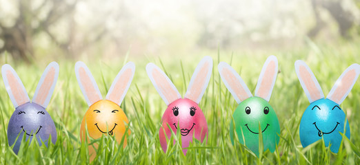 Easter holiday concept with cute handmade eggs, bunnies on the lawn. Banner for design