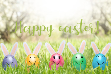 The concept of Easter holiday with cute handmade eggs, rabbits on the lawn. With the inscription happy Easter!