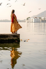 Lonely indian woman in a beautiful dress looks at the lake in Udaipur, Rajasthan, India