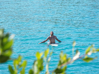 A surfer lies on a surfboard in the ocean.