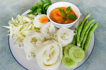 Thai rice noodle or rice vermicelli noodle and curry soup sauce on plate with vegetable