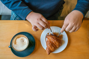 High angle view of woman eating croissant for breakfast