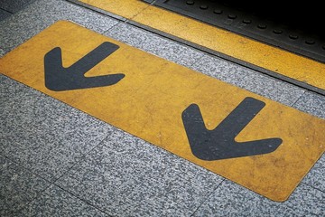 Arrow sign and yellow line on the floor. The symbol at the train platform. - Powered by Adobe