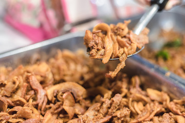 Shredded pork draw up on spoon over a tray with another thing in blurred background