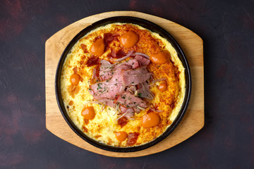 Omelette with bacon and fried onion on cast-iron pan