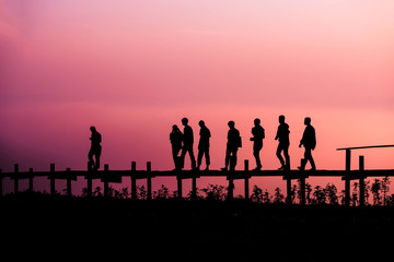 Fototapeta na wymiar Walking people Silhouette team friends group of people walking on the wooden bridge on hill with sunrise or sunset