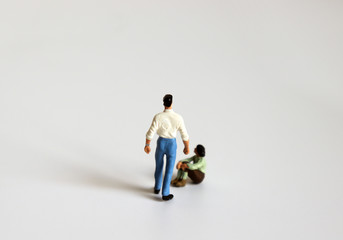 The concept of domestic violence. Miniature man standing and sitting miniature woman.