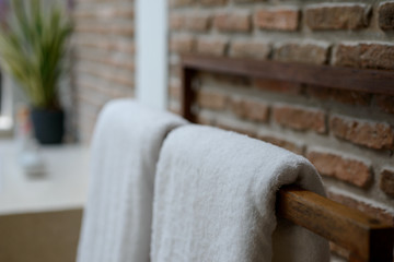 Obraz premium Towels in wooden rack with brick wall background in bathroom