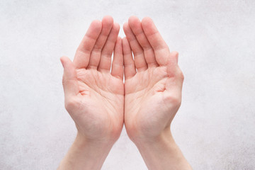 Male hands cupped together on light gray background.
