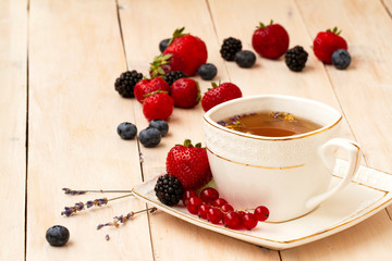 Herbal tea with lavender and mint, fresh strawberries, blackberries and blueberries on a white wooden table. Berry tea with fresh strawberry, blackberry.