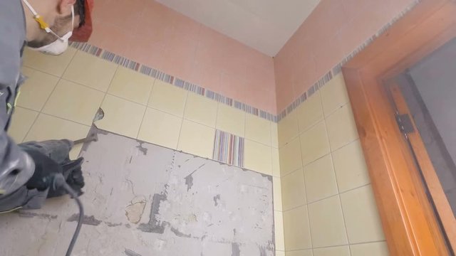 Demolition of old tiles with jackhammer. Renovation of old walls in the bathroom or kitchen