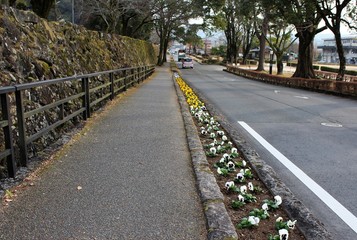 A modern road and remaining medieval castle stone wall coexist in Japan