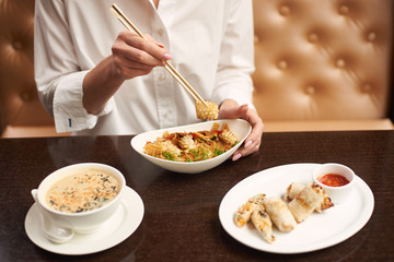 Lady in white blouse sitting in luxury restaurant and eating tasty meal. Three courses lunch from soup, noodles and tempura shrimps on special offer. Girl tasting oriental style dish.
