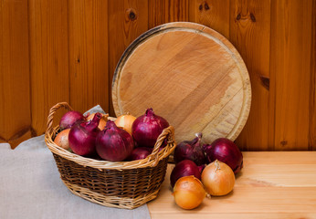 Colorful onions in basket and cutting board as copy space behind. Selective focus.