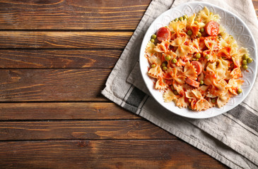 Plate with delicious pasta and sausage on wooden table