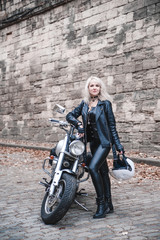Fototapeta na wymiar Beautiful biker woman posing outdoor with motorcycle. 