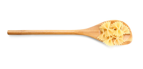 Spoon with uncooked farfalle pasta on white background