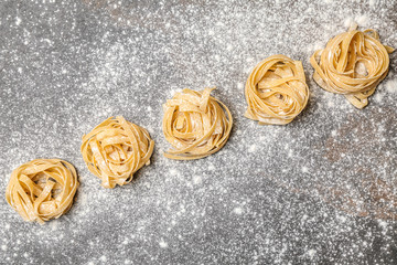 Uncooked noodles with flour on grey background