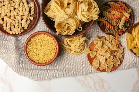 Plates with assortment of uncooked pasta on light table