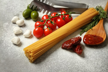 Raw pasta with products on grey background