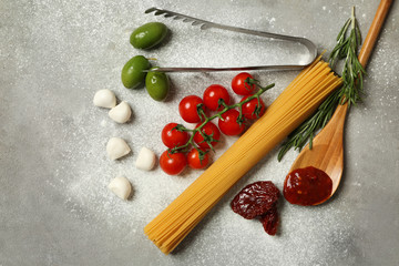 Raw pasta with products on grey background