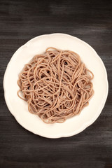 A photo of a plate of soba, buckwheat noodles, shot from above on a black background with a place for text