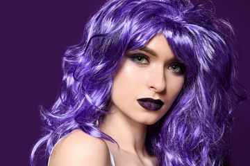 Beautiful young woman with violet wig on color background